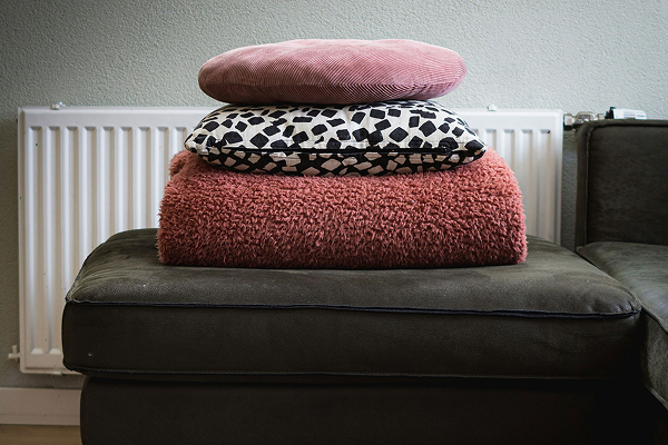 stack of cushions with a folded blanket placed on an ottoman